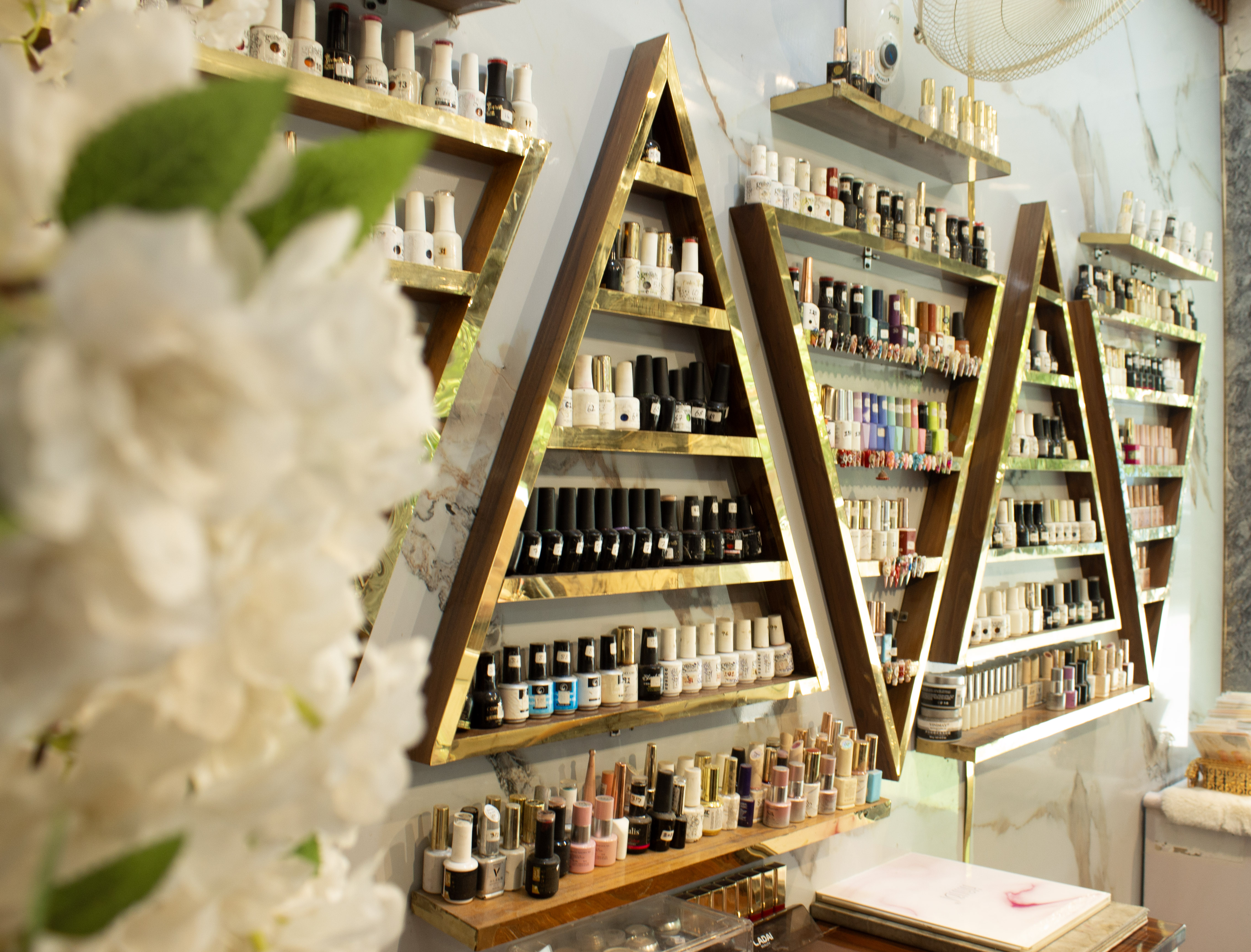 Signature gold triangular nail polish shelves at Nailed It Salon Delhi NCR — 300+ shades